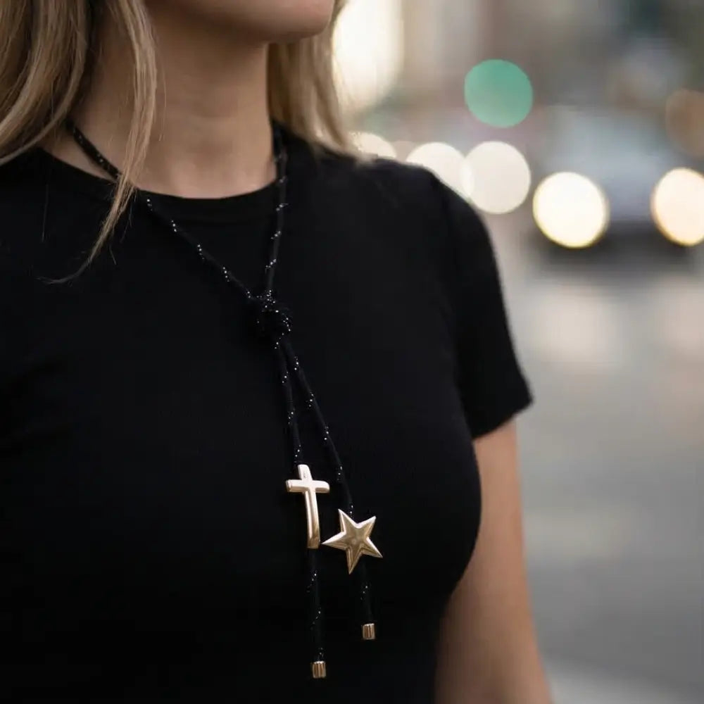 Black paracord necklace with gold cross and star charms worn by woman modern minimalist jewelry by Julie Saldivia